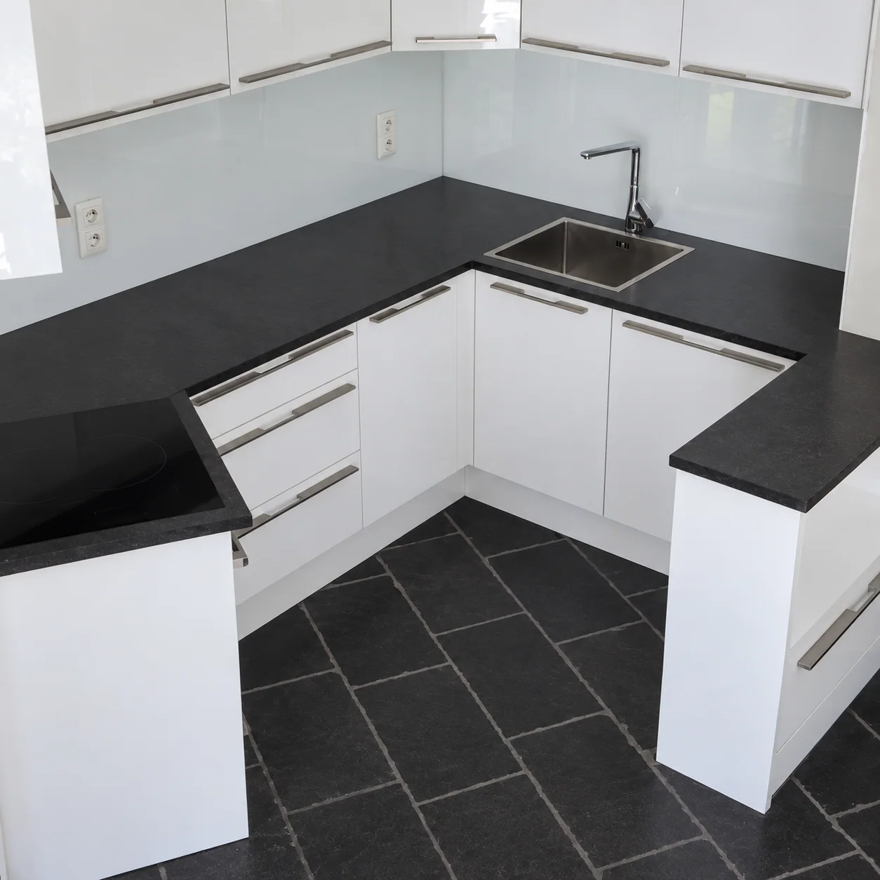 White L-shaped kitchen with a black worktop from the White project